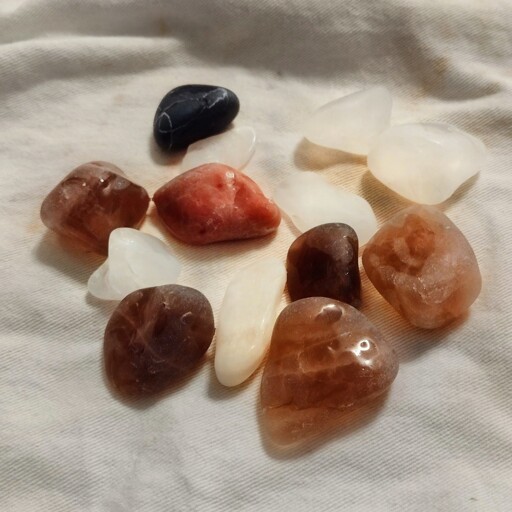 A variety of partially tumbled (smoothed) rocks on a white cloth.
