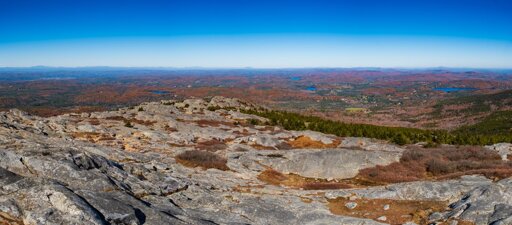 Looking out from the summit (3,156.8 ft) of Mt Monadnock over its stony flanks, forests in fall foliage, to distant mountains.
© Tom Goetz. All rights reserved. Training an AI on this image is expressly forbidden.