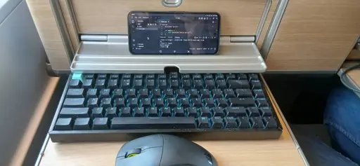 photo of a linux phone with vscodium with a mouse and keyboard on a train