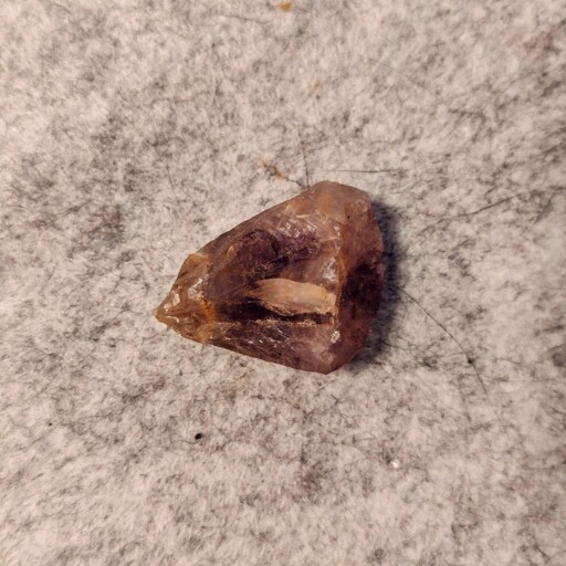 A small piece of amethyst on a felt mat.