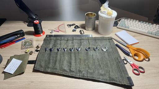 Here you can see the materials and tools used to create this wrench wrap. Includes: fabric, clips, pins, thread, pencil, pen, needle, seam cutter, paraffin, beeswax, scraps from backpacks, chalk, scissors, ruler.